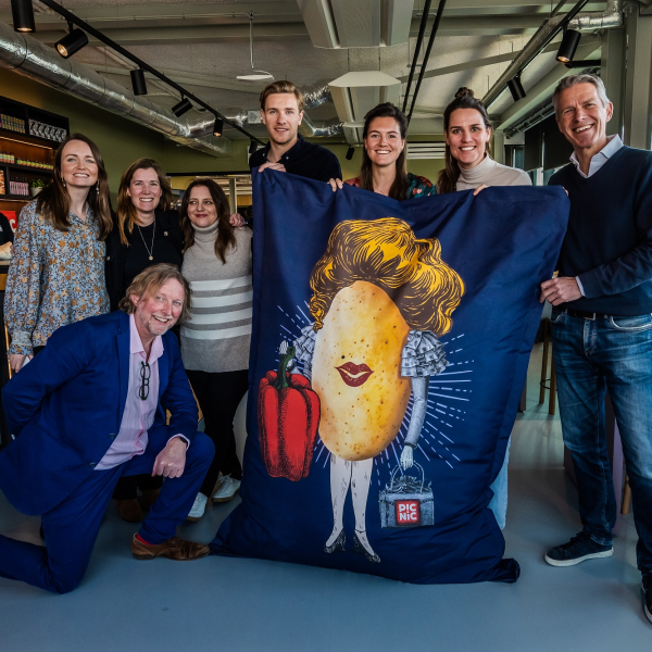 A group of smiling people gather round a Picnic branded bean bag chair.
